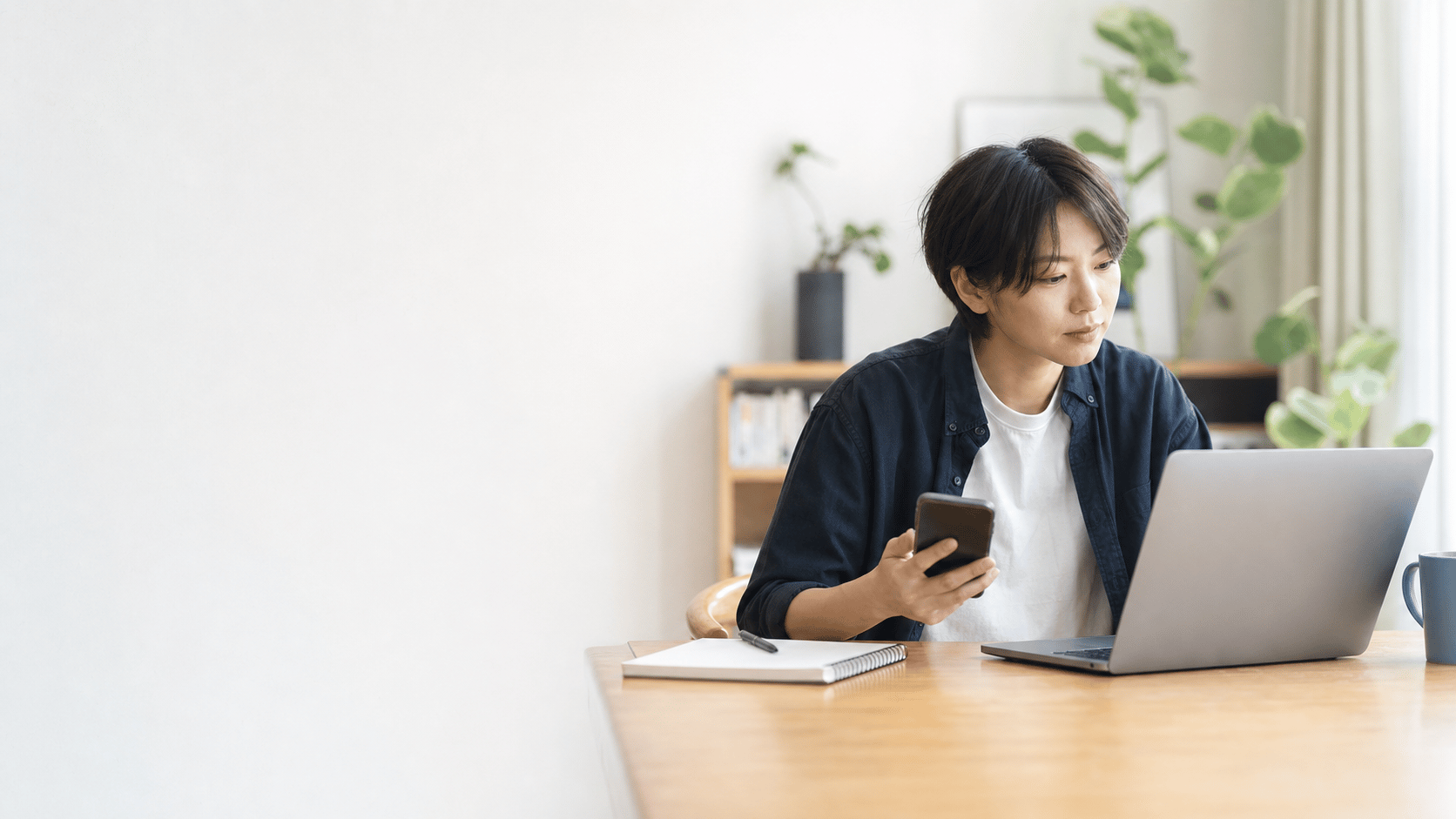 自宅でスマートフォンとパソコンを使い求人情報を確認する人